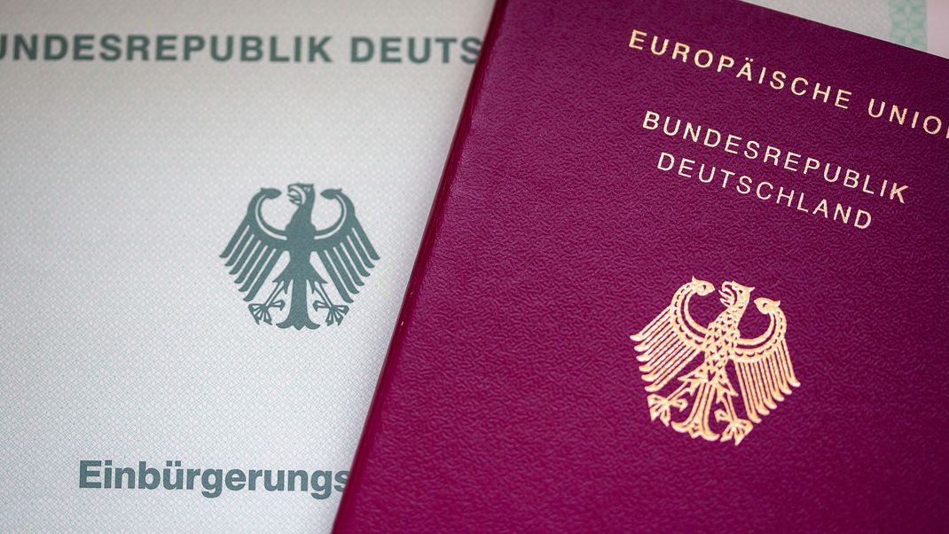 Eine Einbürgerungsurkunde der Bundesrepublik Deutschland (l.) und ein deutscher Reisepass liegen auf einem Tisch.