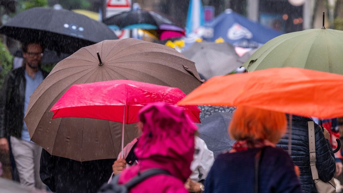 Passanten laufen mit Regenschirmen durch die Innenstadt von München.