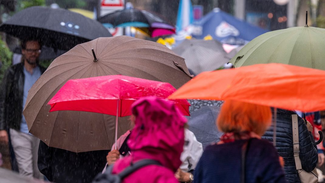 Passanten laufen mit Regenschirmen durch die Innenstadt von München.
