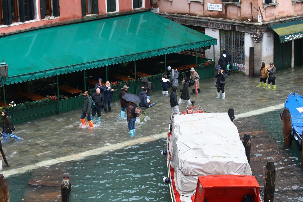 Touristen und Einheimische kämpften sich mit Gummistiefeln und wasserfester Kleidung durch die gefluteten Straßen.