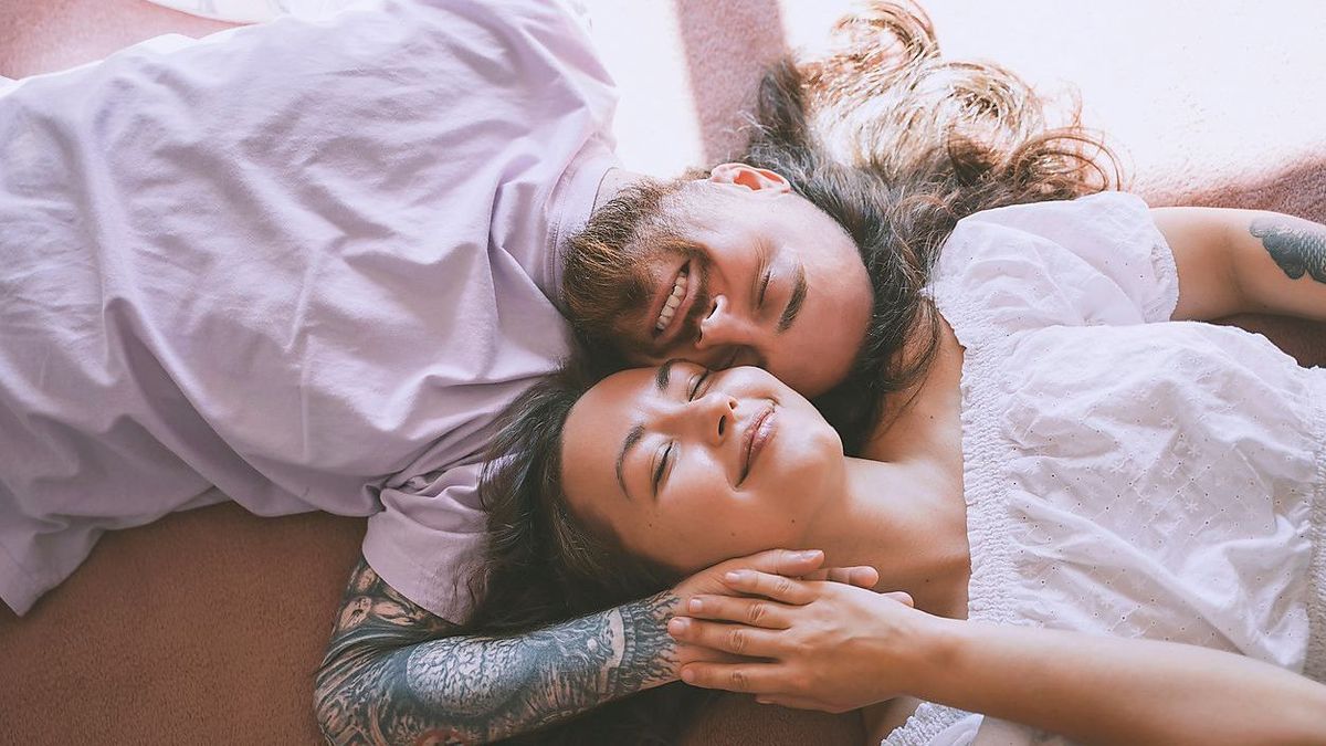 Happy romantic couple with eyes closed lying on bed at home