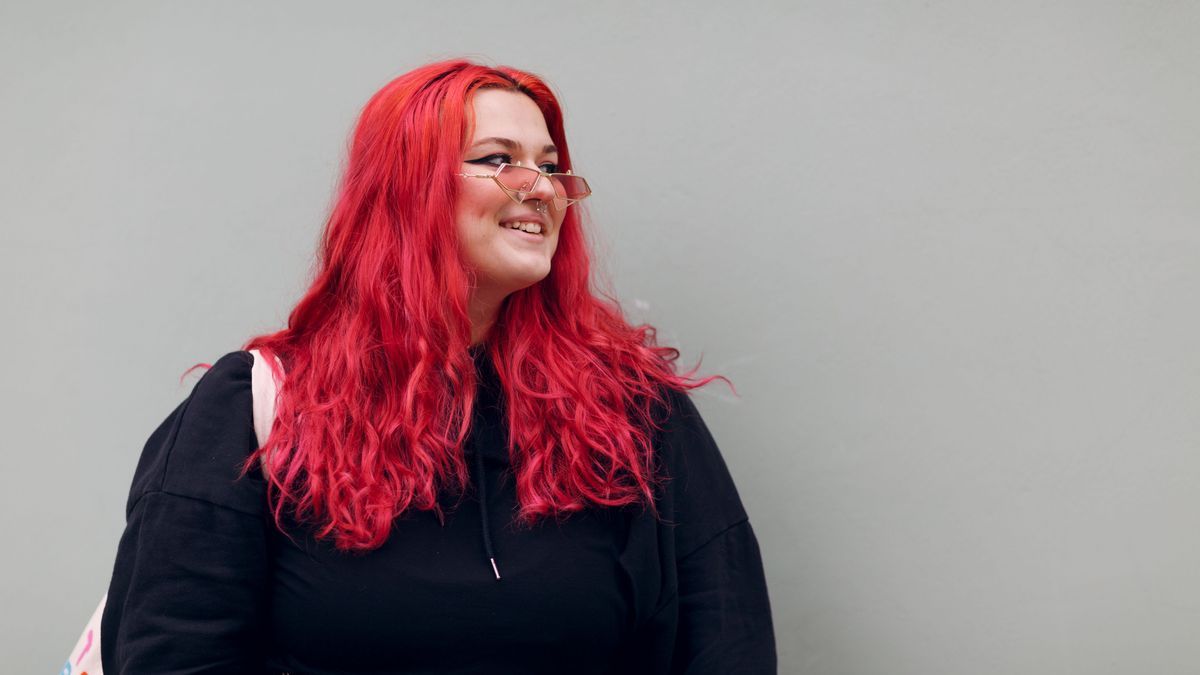 Plus size overweight fat body positive lgbtq woman with red hair and pink glasses.