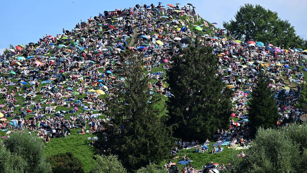 27. Juli 2024, Bayern, München: Fans sitzen auf dem Olympiaberg im Olympiapark und warten auf den Beginn des ersten Konzerts von Taylor Swift. Am Sonntag, 28. Juli, findet dort Swifts zweiter Auftritt in München statt, das letzte ihrer Deutschlandkonzerte im Rahmen der "The Eras Tour".