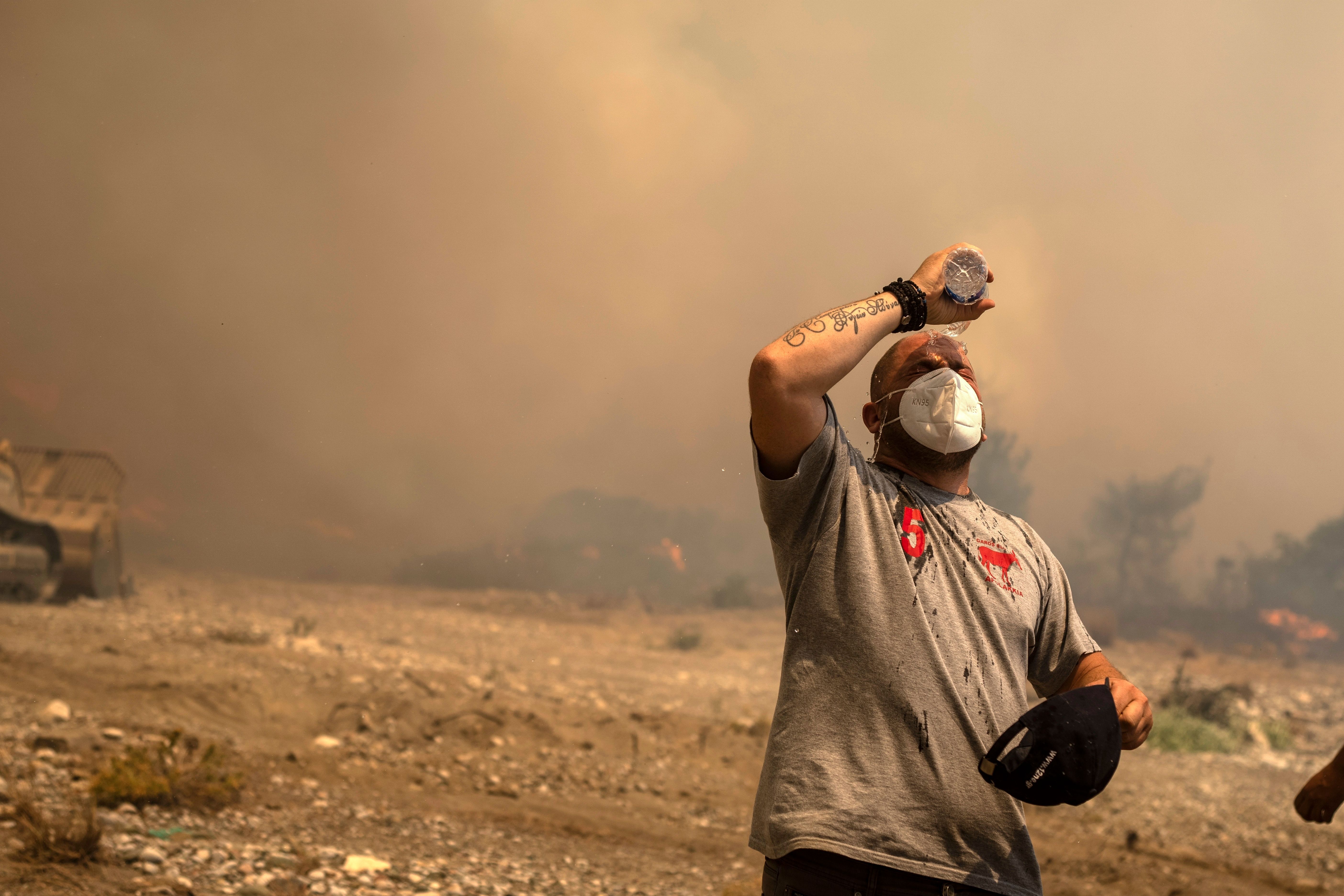 25. Juli 2023: Ein freiwilliger Helfer kühlt sich während eines Waldbrandes in der Ortschaft Vati auf der griechischen Insel Rhodos ab.