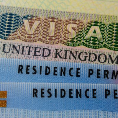 United Kingdom BRP (Biometrical Residence Permit) cards for Tier 2 work visa placed on top of UK VISA sticker in the passport. Close up photo.