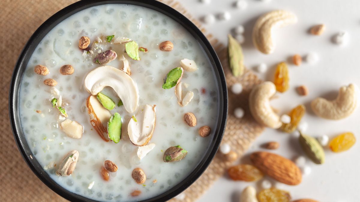Close-up of Creamy Sabudana Kheer Garnished with dry fruits. Indian delicious dessert. Served in a black bowl. Top View on wooden background.