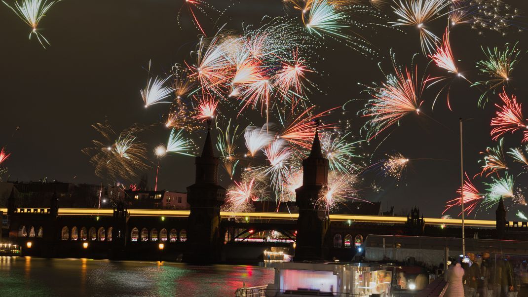 Feuerwerkskörper gehen an Silvester hinter der Oberbaumbrücke in den Nachthimmel hoch.