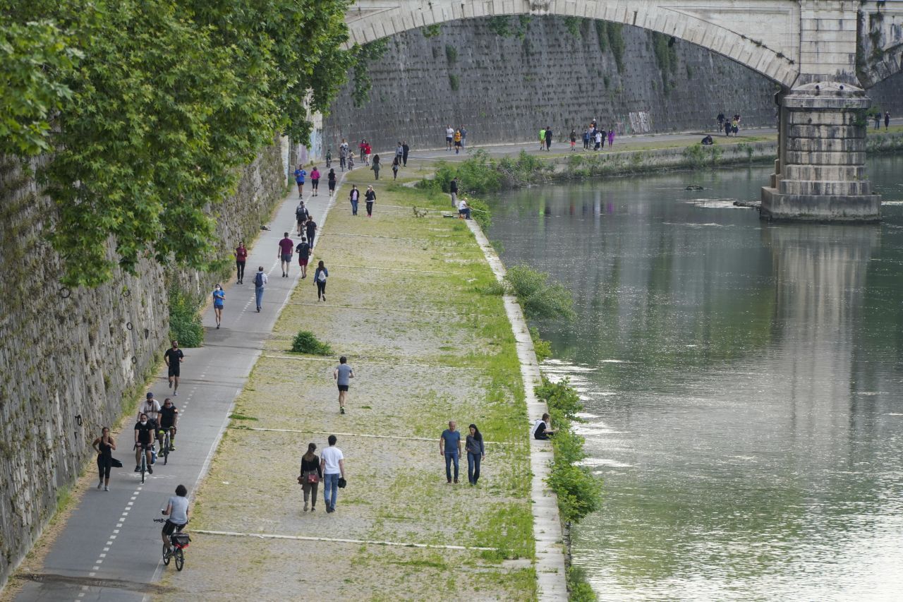 Italien, Rom: Die Maßnahmen zur Eindämmung der Corona-Pandemie werden langsam gelockert werden - Menschen spazieren am Fluss Tiber. 