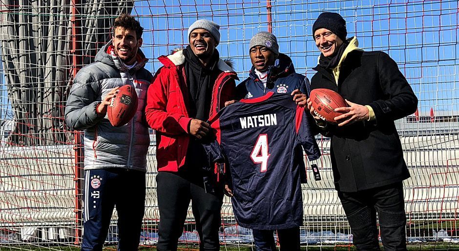 
                <strong>Deshaun Watson besucht Deutschland</strong><br>
                Gruppenbild mit NFL-Profi: Zum Abschluss schenkt Watson (2. v. l.) den Bayern noch ein Trikot mit der Nummer 4. Hier darf David Alaba (2. v. r.) das gute Stück in Händen halten. Ob Martinez (l.) und Lewandowski auch einmal zugreifen dürfen?
              