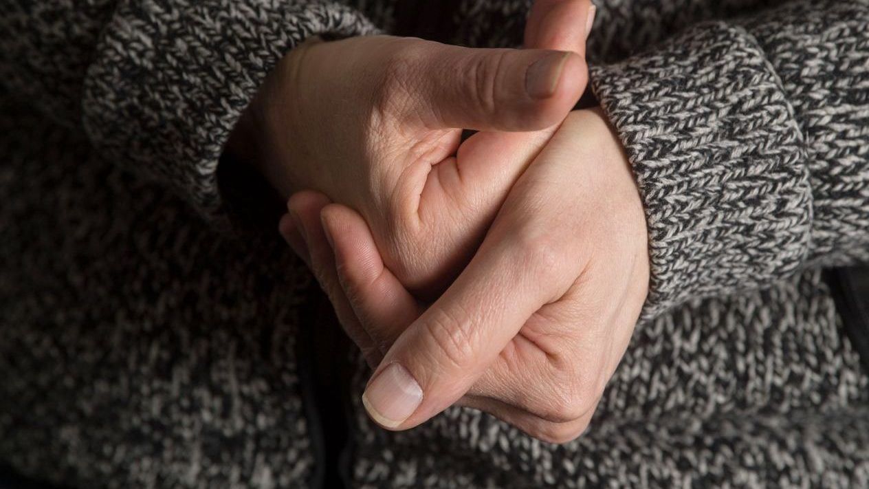 Zwei Hände vor einem grau melierten Pulli beim Fingerknacken.
