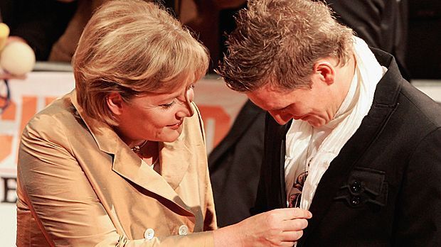 
                <strong>Hallo, Frau Bundeskanzlerin</strong><br>
                Auch Bundeskanzlerin Angela Merkel fühlt nach dem Sommermärchen bei der Heim-WM 2006 bei Schweinsteiger vor.
              