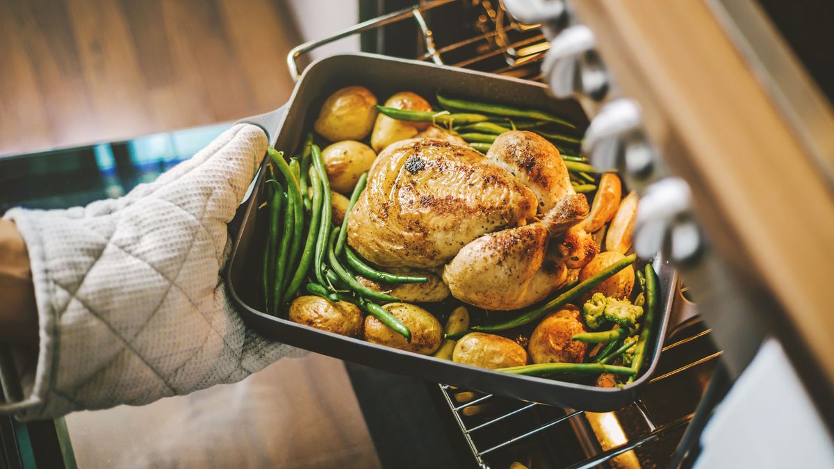 Cook taking ready chicken from the oven 