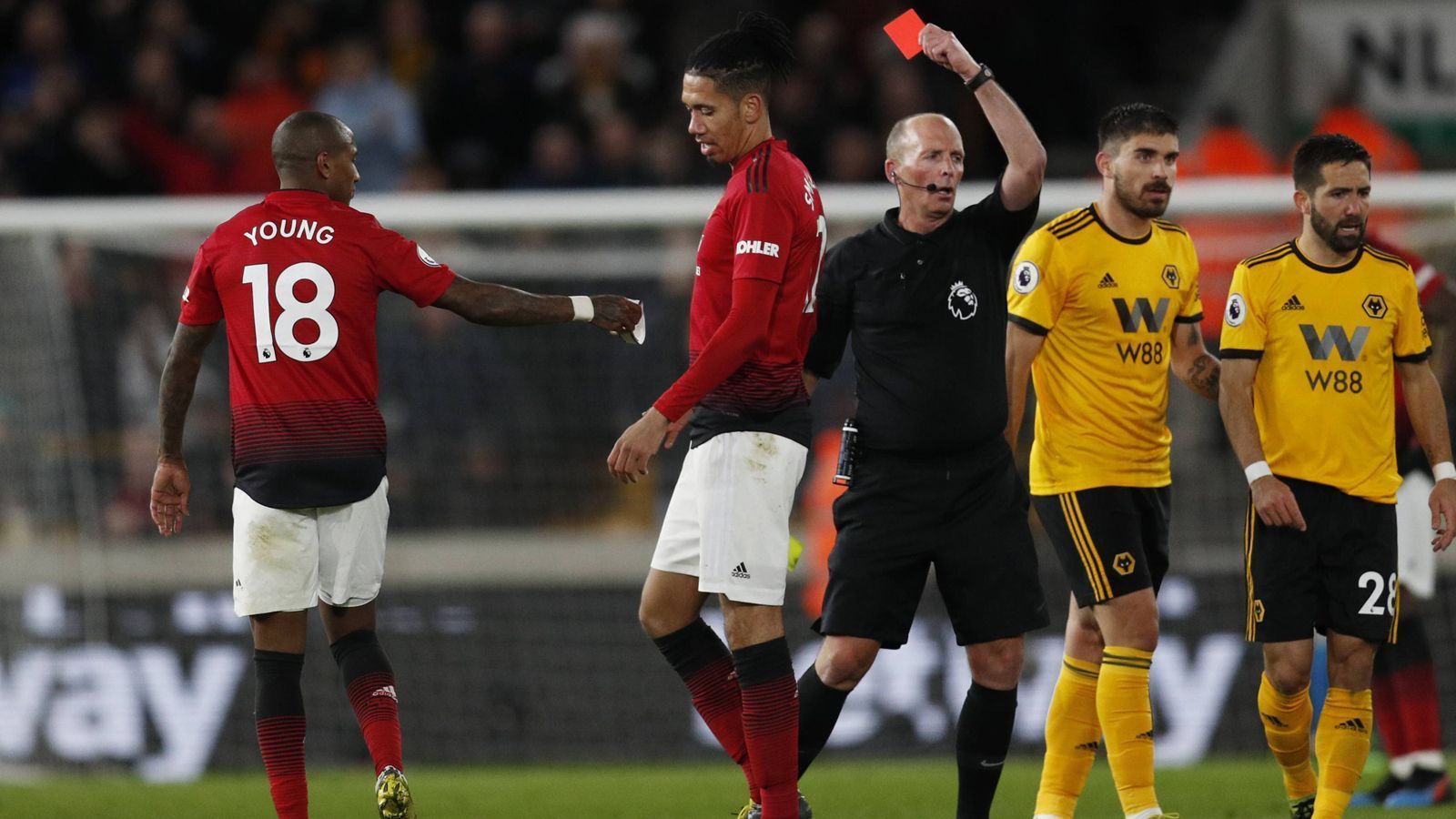 
                <strong>Premier-League-Schiedsrichter Mike Dean knackt Rot-Rekord</strong><br>
                Bei Manchester Uniteds 1:2-Niederlage bei Aufsteiger Wolverhampton stand Schiedsrichter Mike Dean (Mi.) im Mittelpunkt. Der 50-Jährige stellte Uniteds Ashley Young (li.) in der 57. Minute mit Gelb-Rot vom Platz. Es war der 100. Platzverweis, den Dean damit in seiner Premier-League-Laufbahn aussprach. Damit zeigte der Unparteiische mehr Gelb-Rote und Rote Karten als jeder andere Referee in der Historie der Premier League. (Quelle: Optajoe/twitter)
              