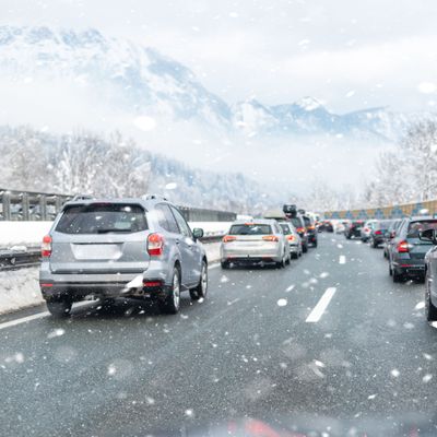 Winter highway with many different cars stucked in traffic jam due ti bad weather conditions. Vehicles on road during heavy snowstorm and blizzard on cold winter day in Austria near Germany border