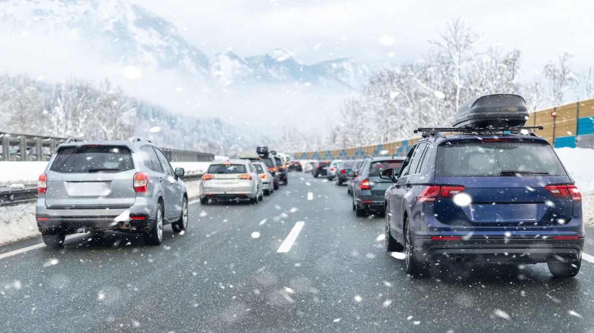 Winter highway with many different cars stucked in traffic jam due ti bad weather conditions. Vehicles on road during heavy snowstorm and blizzard on cold winter day in Austria near Germany border