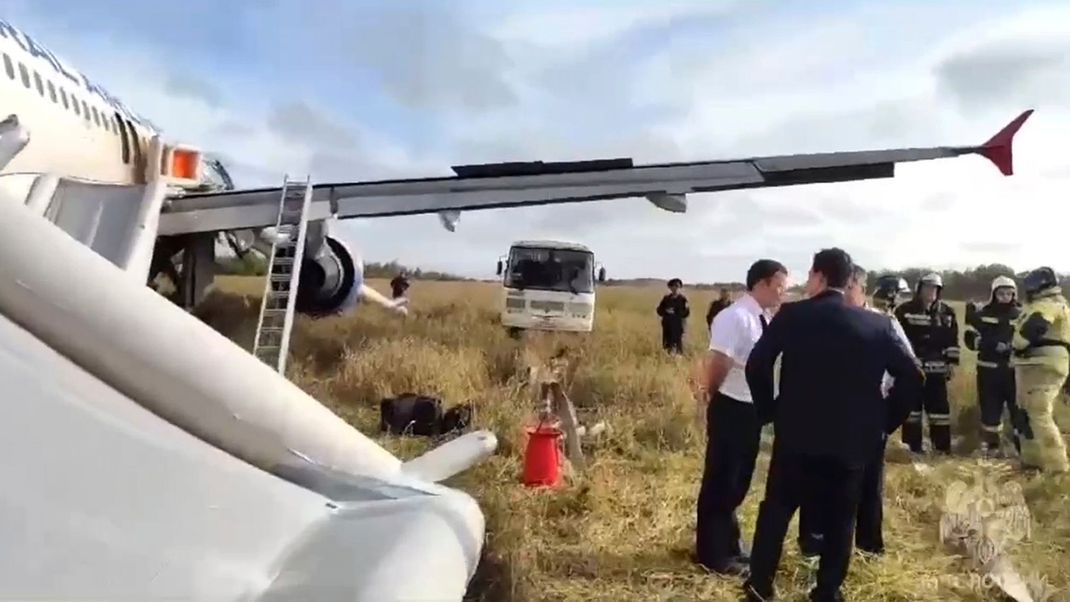 Rettungskräfte und Ermittler neben dem Airbus A320 der Ural Airlines nach der Notlandung in der Nähe des Dorfes Ubinskoje in der Region Nowosibirsk, Russland.