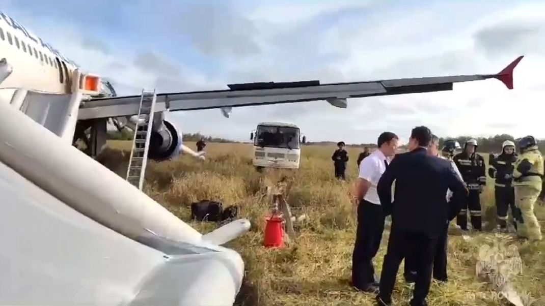 Rettungskräfte und Ermittler neben dem Airbus A320 der Ural Airlines nach der Notlandung in der Nähe des Dorfes Ubinskoje in der Region Nowosibirsk, Russland.