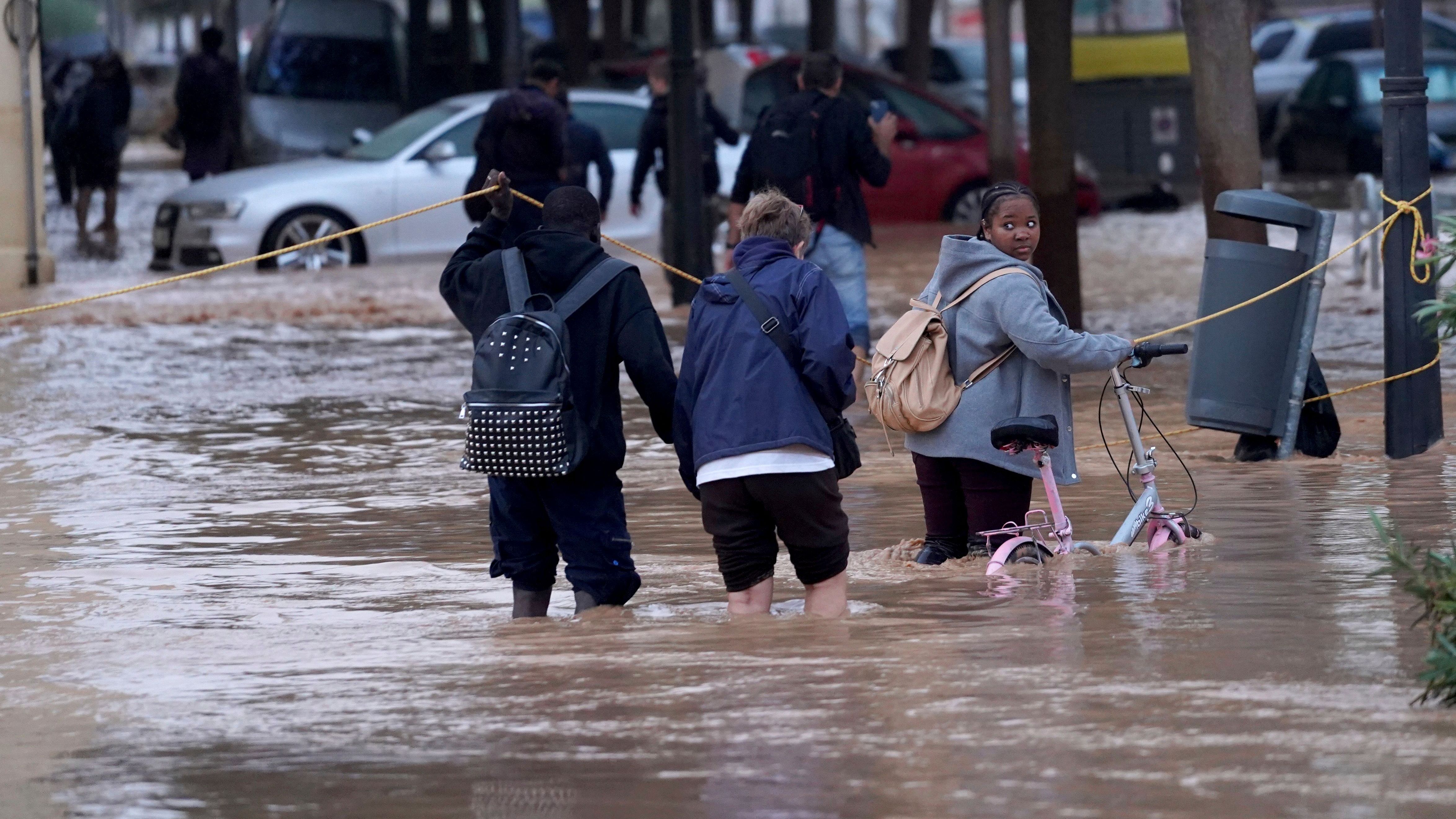 Menschen gehen durch überflutete Straßen in Valencia.