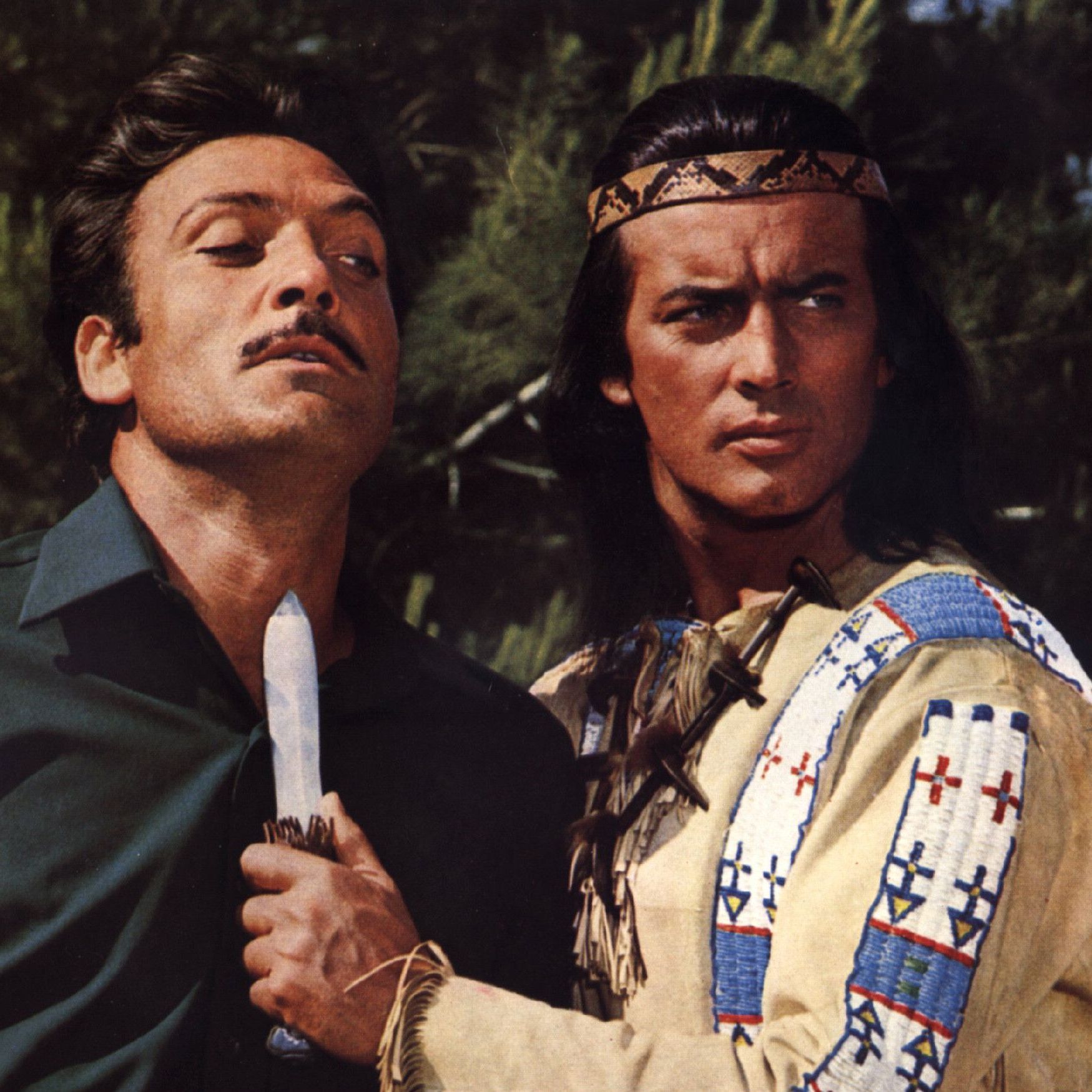 Winnetou bedroht einen Mann mit einem Messer. Er hält es an seinen Hals.