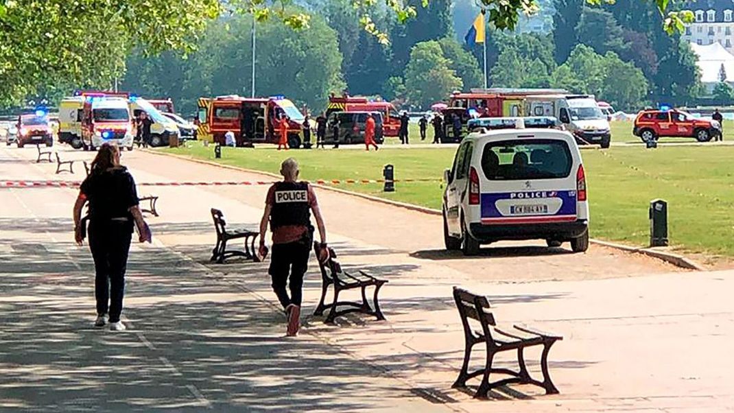 Polizisten und Rettungskräfte gehen nach einem Messerangriff in einem französischen Park zum Tatort. 