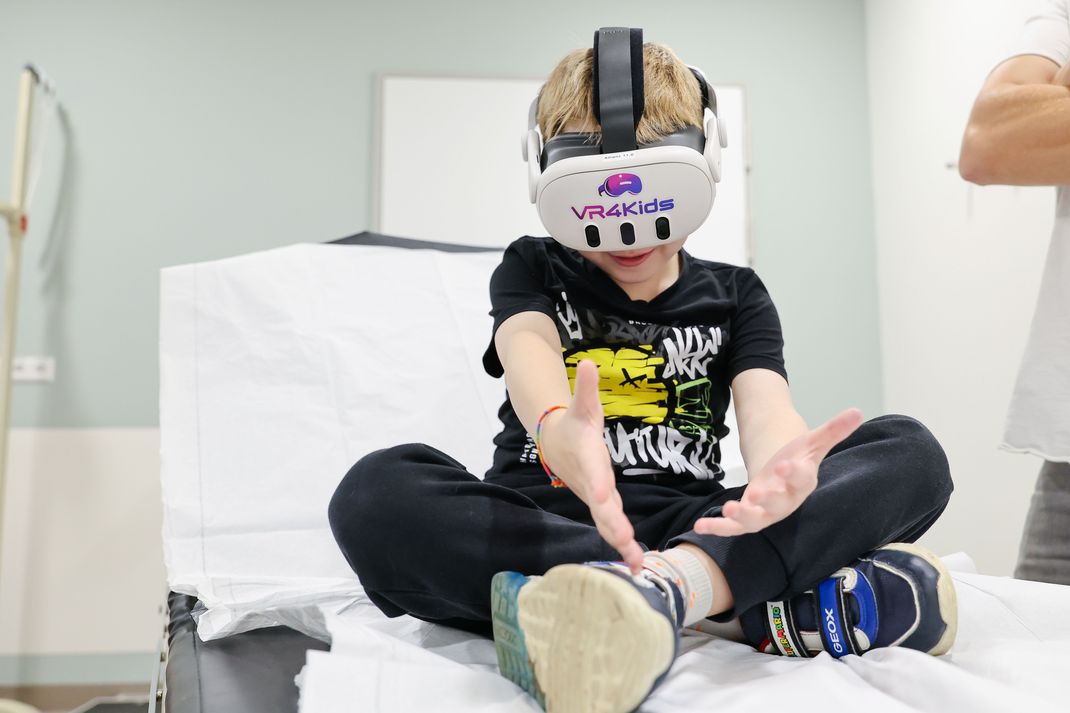 17.09.2025, Bayern, München: Kenan Bas schaut im München Klinikum Schwabing 360 Grad Videos vom Oktoberfest mit eine Virtual Reality-Brille von „VR4Kids“ und kann sich so von der Untersuchung ablenken. Das Ziel der 360° Technologie ist es, Nutzern das Gefühl zu vermitteln, aktiv mitten im Geschehen zu stehen und damit die Inklusion zu fördern.

Kenan ist im Krankenhaus, aber mit der VR-Brille kann er trotzdem das Oktoberfest besuchen.  (zu dpa: «Vom Krankenbett aus Riesenrad fahren») Foto: Daniel Löb/dpa - Honorarfrei nur für Bezieher des Dienstes dpa-Nachrichten für Kinder +++ dpa-Nachrichten für Kinder +++