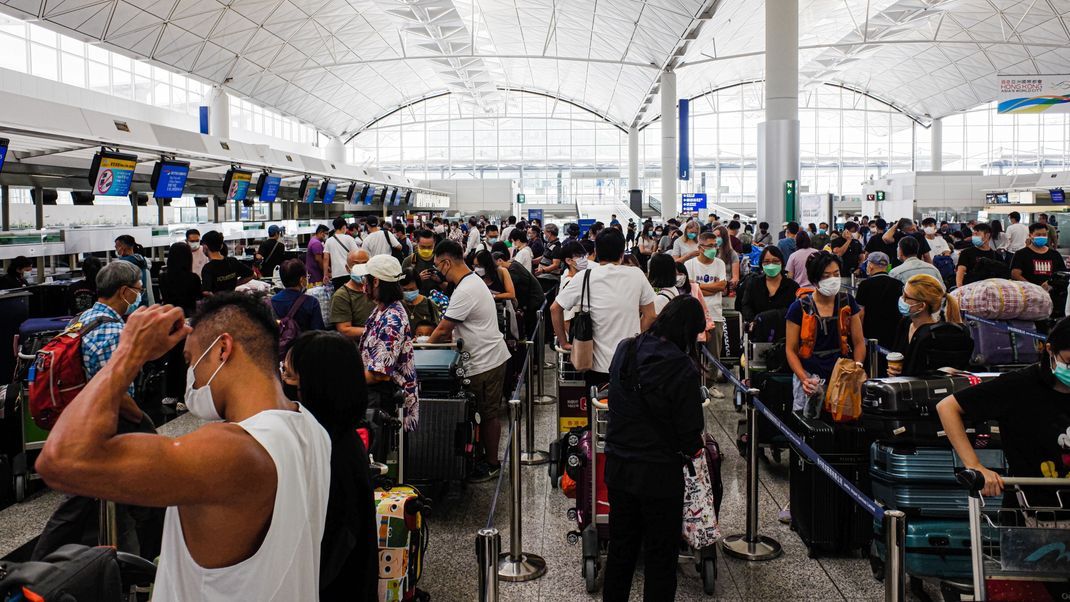 Menschen stehen am internationalen Flughafen von Hongkong vor ihrer Abreise Schlange. 