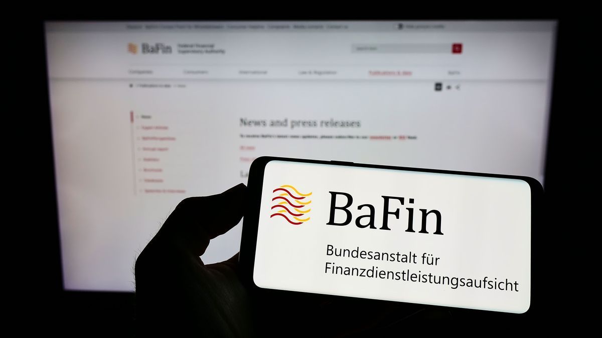 Stuttgart, Germany - 07-15-2022: Person holding cellphone with logo of German financial supervisory authority BaFin on screen in front of webpage. Focus on phone display. 