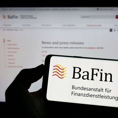 Stuttgart, Germany - 07-15-2022: Person holding cellphone with logo of German financial supervisory authority BaFin on screen in front of webpage. Focus on phone display. 