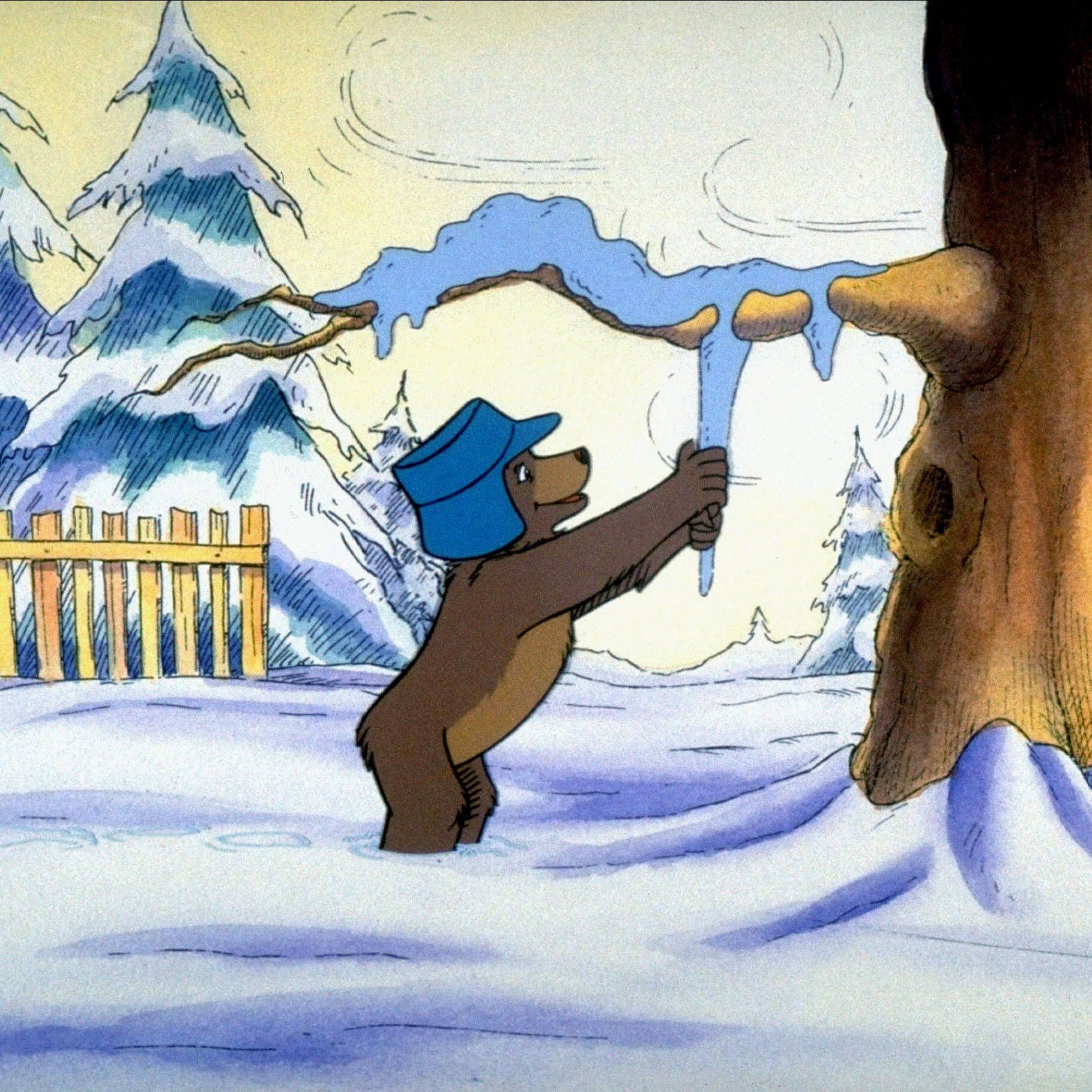 Der kleine Bär zeiht an einem Eiszapfen in einem verschneitem Wald.