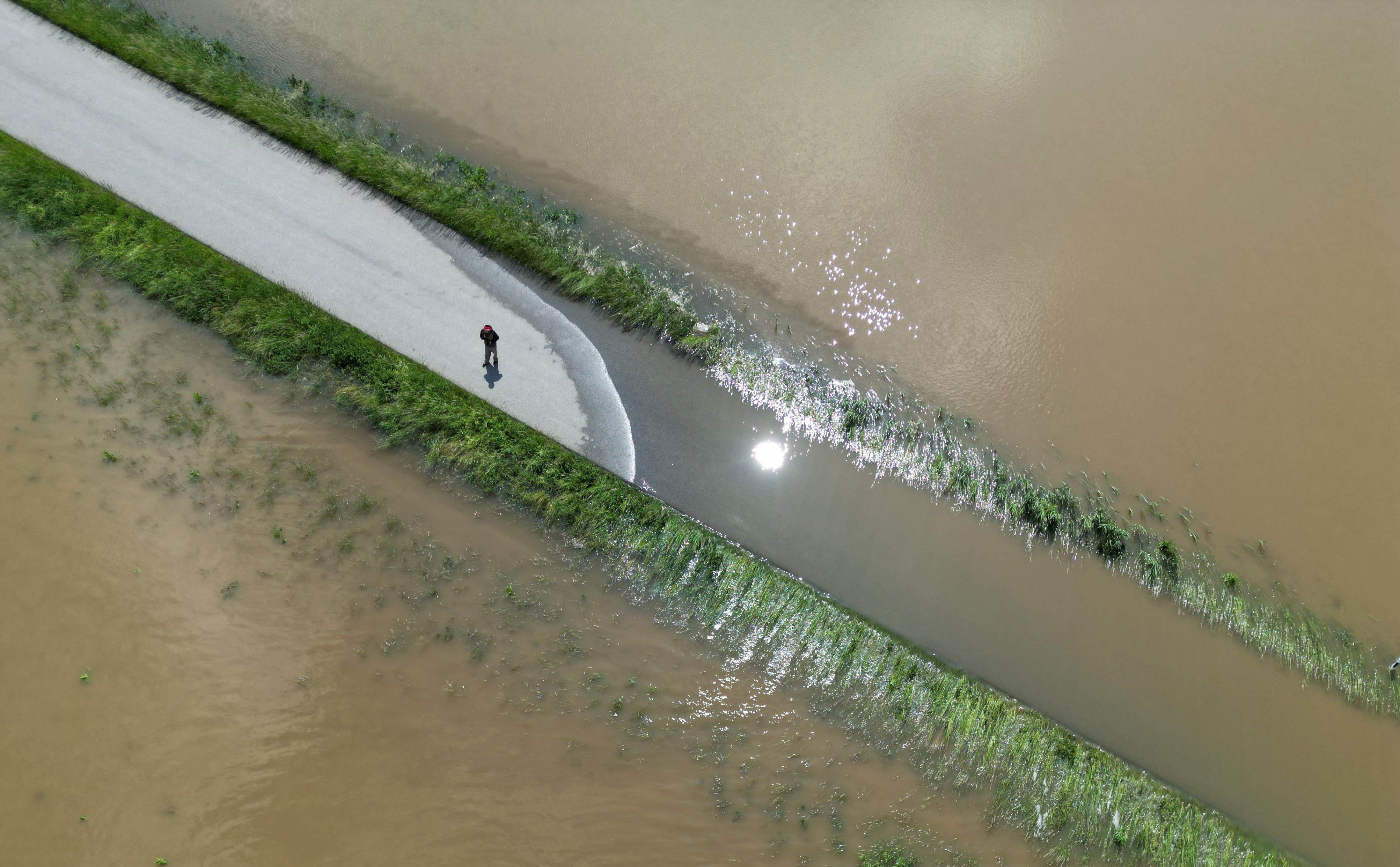 Der Fluss Glenn ist bei Eglhausen in der Gemeinde Hohenkammer über die Ufer getreten und überschwemmt Wiesen, Felder und eine Straße, auf der ein Mensch steht (Aufnahmen mit einer Drohne). 