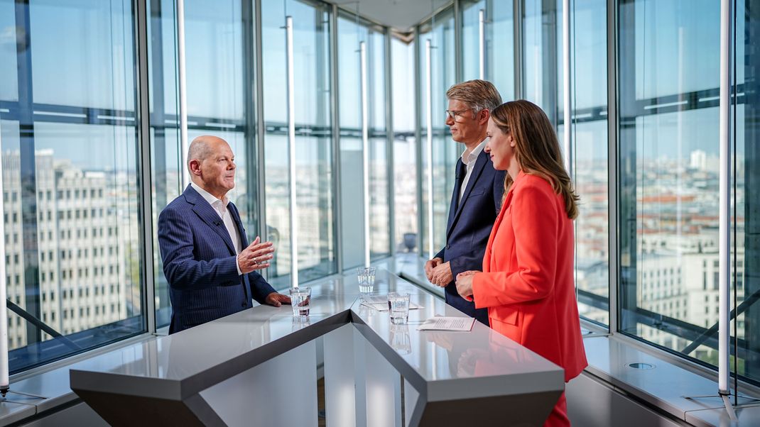 Bundeskanzler Olaf Scholz (l, SPD) spricht beim Fernsehsender Sat.1 in einem Interview mit Charlotte Potts (r) und Heiko Paluschka (M). Ausgestrahlt wird das Gespräch mit dem Politiker in der Sendung :newstime spezial - «Wo steht Deutschland? 