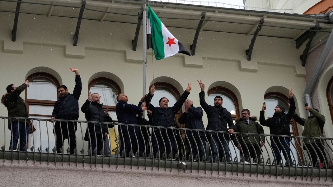 Mitglieder der syrischen Diaspora feiern beim Hissen der syrischen Oppositionsflagge an der syrischen Botschaft in Moskau.