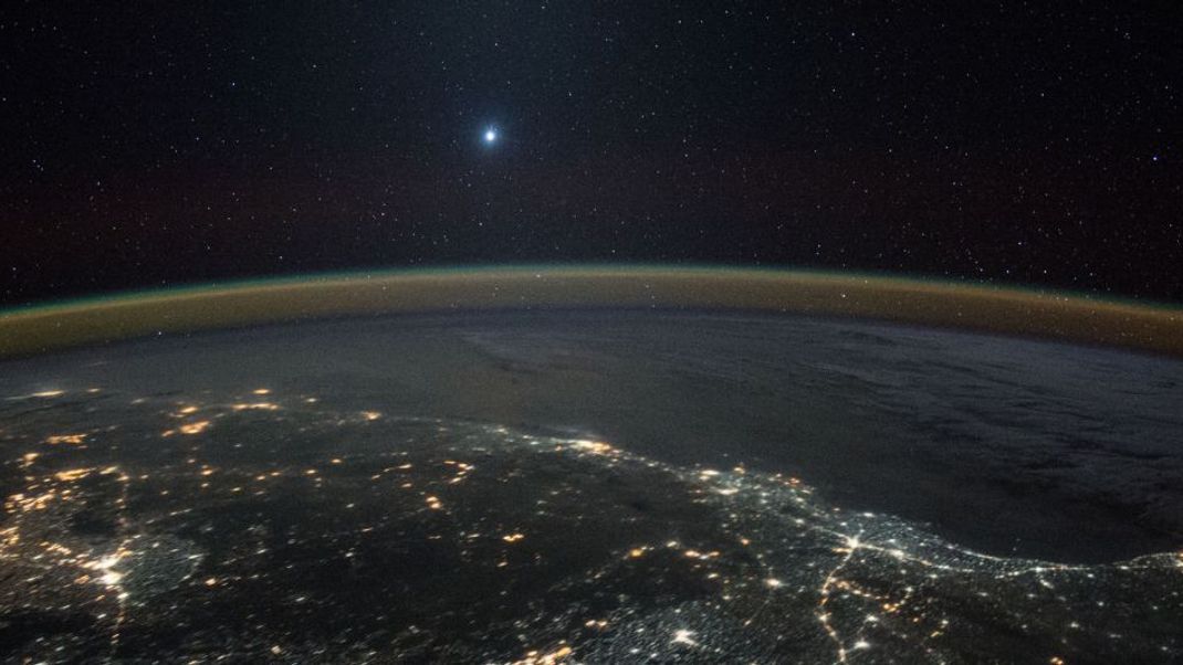 Venus über der Erde, 2015 fotografiert von der ISS aus: Nach Sonne und Mond ist die Venus das hellste Objekt am Himmel. Steht sie weit genug von der Sonne entfernt, ist sie bei günstigen Bedingungen sogar am Taghimmel zu sehen.