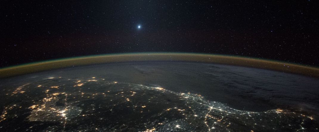 Venus über der Erde, 2015 fotografiert von der ISS aus: Nach Sonne und Mond ist die Venus das hellste Objekt am Himmel. Steht sie weit genug von der Sonne entfernt, ist sie bei günstigen Bedingungen sogar am Taghimmel zu sehen.