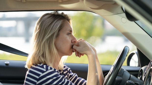 Frau mittleren Alters sitzt gestresst im Auto; Burnout