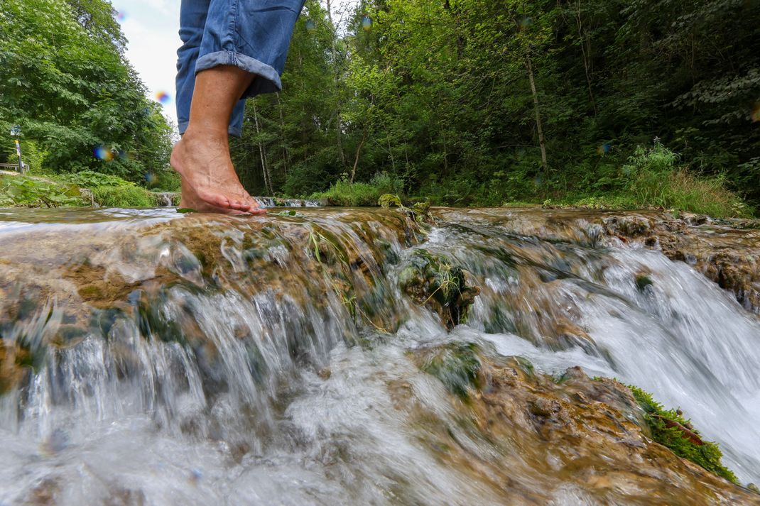 Eine Ausflüglerin nimmt bei Temperaturen um die 29 Grad auf der Schwäbischen Alb ein Fußbad. (Symbolbild)