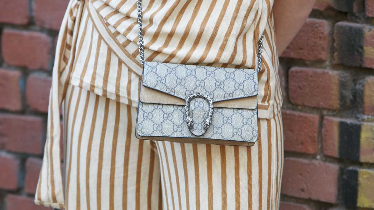 MILAN, ITALY - SEPTEMBER 20, 2018: Woman with white and brown striped dress and Gucci bag before Fendi fashion show, Milan Fashion Week street style