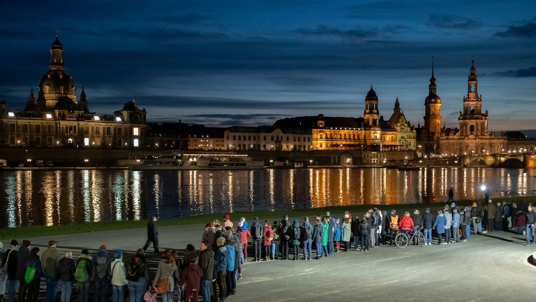 Mehrere tausend Menschen schließen für zehn Minuten eine Menschenkette rund um die Altstadt mit den Glockenschlägen der Dresdner Kirchen um 18 Uhr.