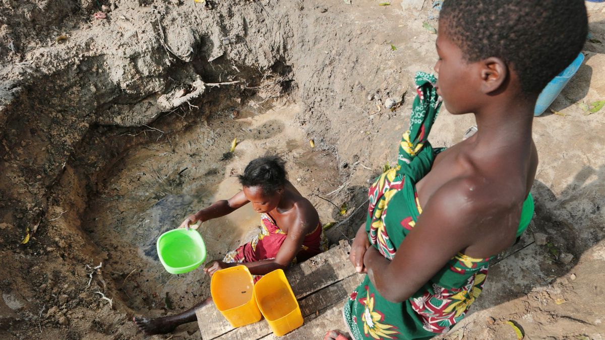 Eine Frau in Mosambik holt Wasser aus einer ungeschützten Quelle.