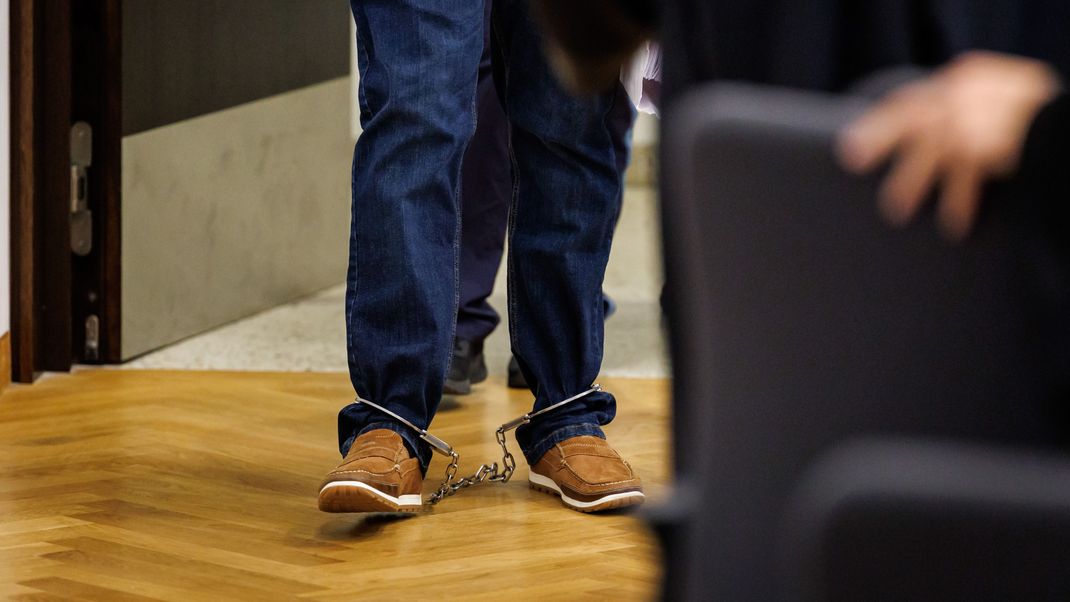 Mit Fußfesseln betritt ein angeklagter Mann zum Prozessbeginn den Sitzungssaal des Strafjustizzentrums des Landgerichts Nürnberg-Fürth.