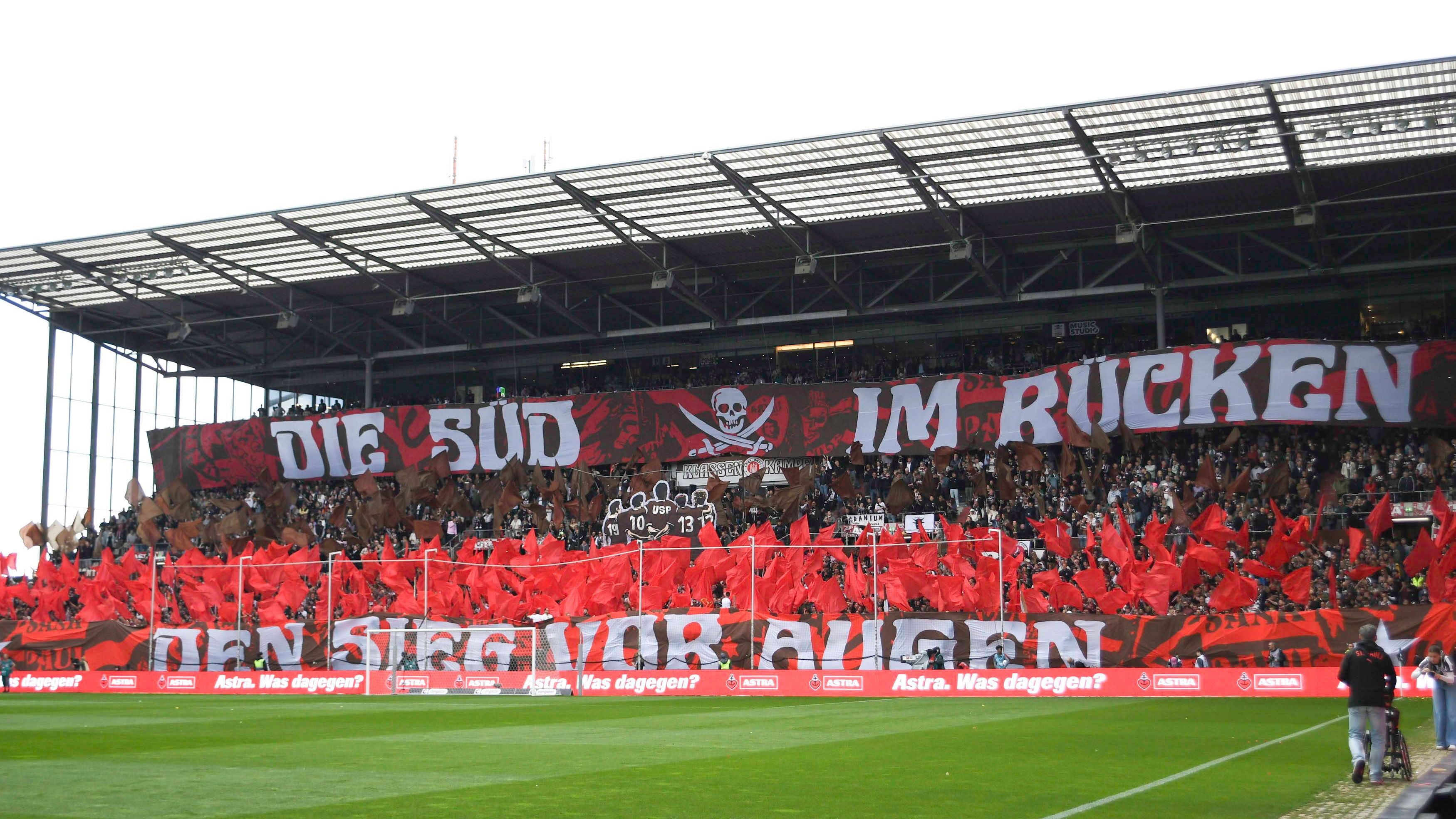 <strong>FC St. Pauli</strong><br>Der FC St. Pauli blieb sich treu. Naja, fast. Heißt jetzt <strong>SPK Hamburg</strong> (St. Pauli Kollektiv), wird aber von einem nachhaltigen Tech-Kollektiv finanziert, das Stadion läuft mit Algenstrom. Die Fans sind dieselben, dafür gibt’s jetzt vegane Fischbrötchen.