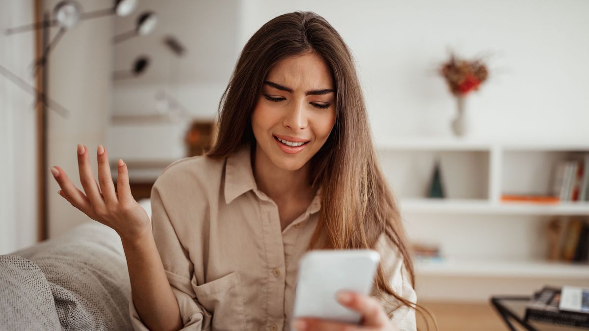 Eine Frau schaut unglücklich auf ihr Handy