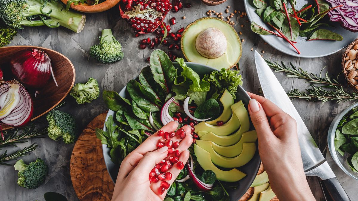 Frauenhände, die einen frischen Salat zubereiten; gesunde Zutaten