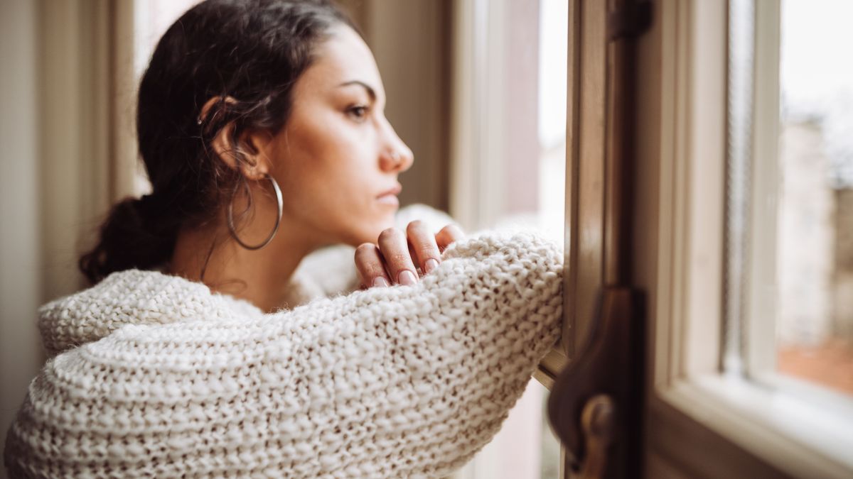 Frau schaut nachdenklich aus dem Fenster