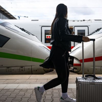 Eine Reisende geht am Hauptbahnhof in München an ICE-Zügen vorbei den Bahnsteig entlang.