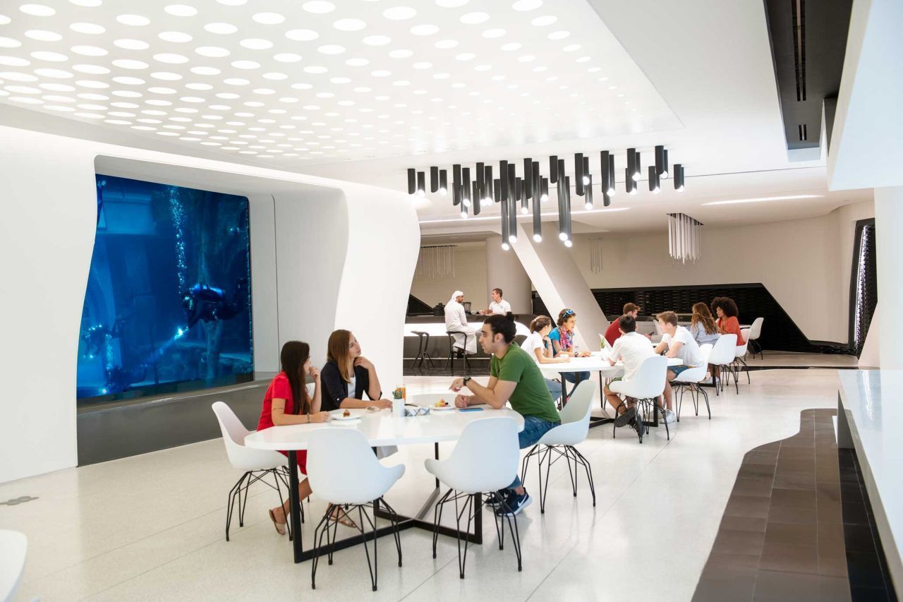 Das Innere des Deep Dive Dubai ist sehr futuristisch. Im Restaurant können sich Besucher:innen stärken und dabei den Tauchenden im Pool zuschauen.