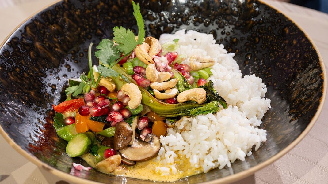 Buntes Gemüse-Curry auf Reis, gerösteter Pak Choi garniert mit Granatapfelkernen und Cashewnüssen.