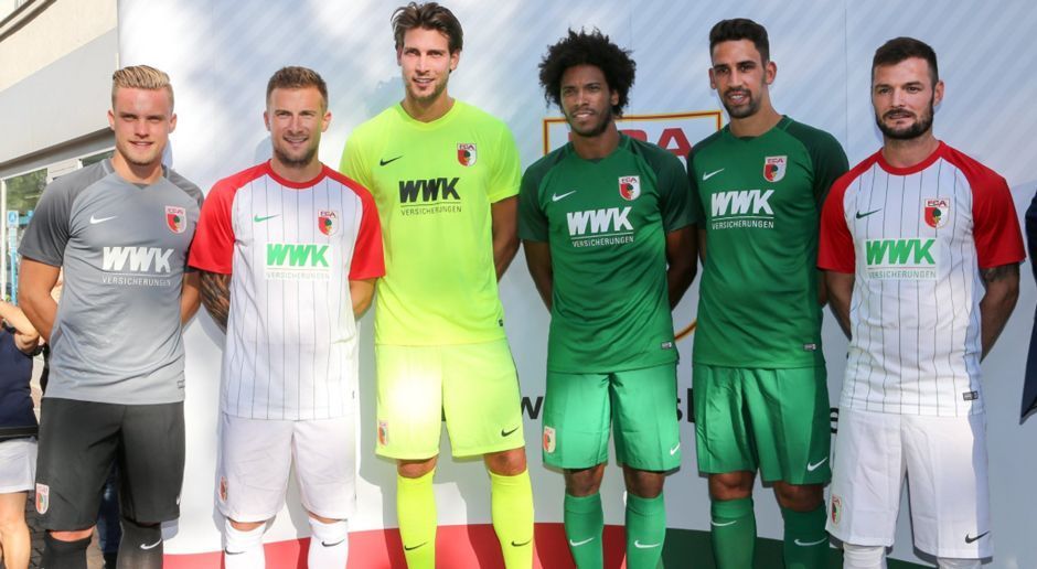 
                <strong>FC Augsburg</strong><br>
                Der FC Augsburg hat auch die neuen Trikots für die Saison 2017/18 präsentiert. Während die Heim-Trikots in Rot-Weiß gehalten sind, werden die Torhüter um Neuzugang Fabian Giefer (3.v.l.) in Gelb auflaufen. Auswärts sind die Fuggerstädter dann planmäßig in Grün zu sehen. Natürlich präsentierte der Bundesligist für den Fall der Fälle auch ein Ausweichstrikot, welches in Grau gehalten wurde.
              