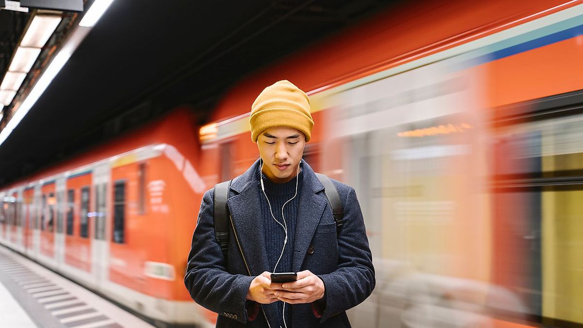 Stylish man with smartphone and earphones in metro station