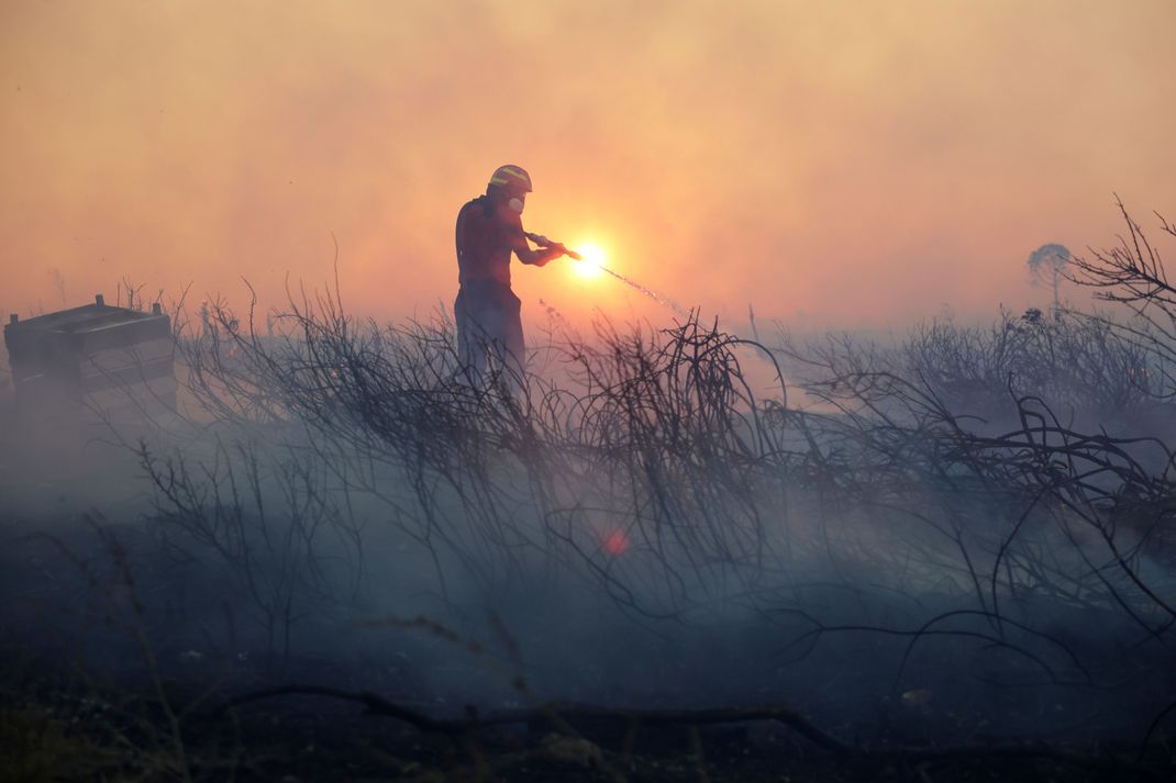 Ein Feuerwehrmann versucht, einen Brand in der Nähe eines Athener Vororts zu löschen.